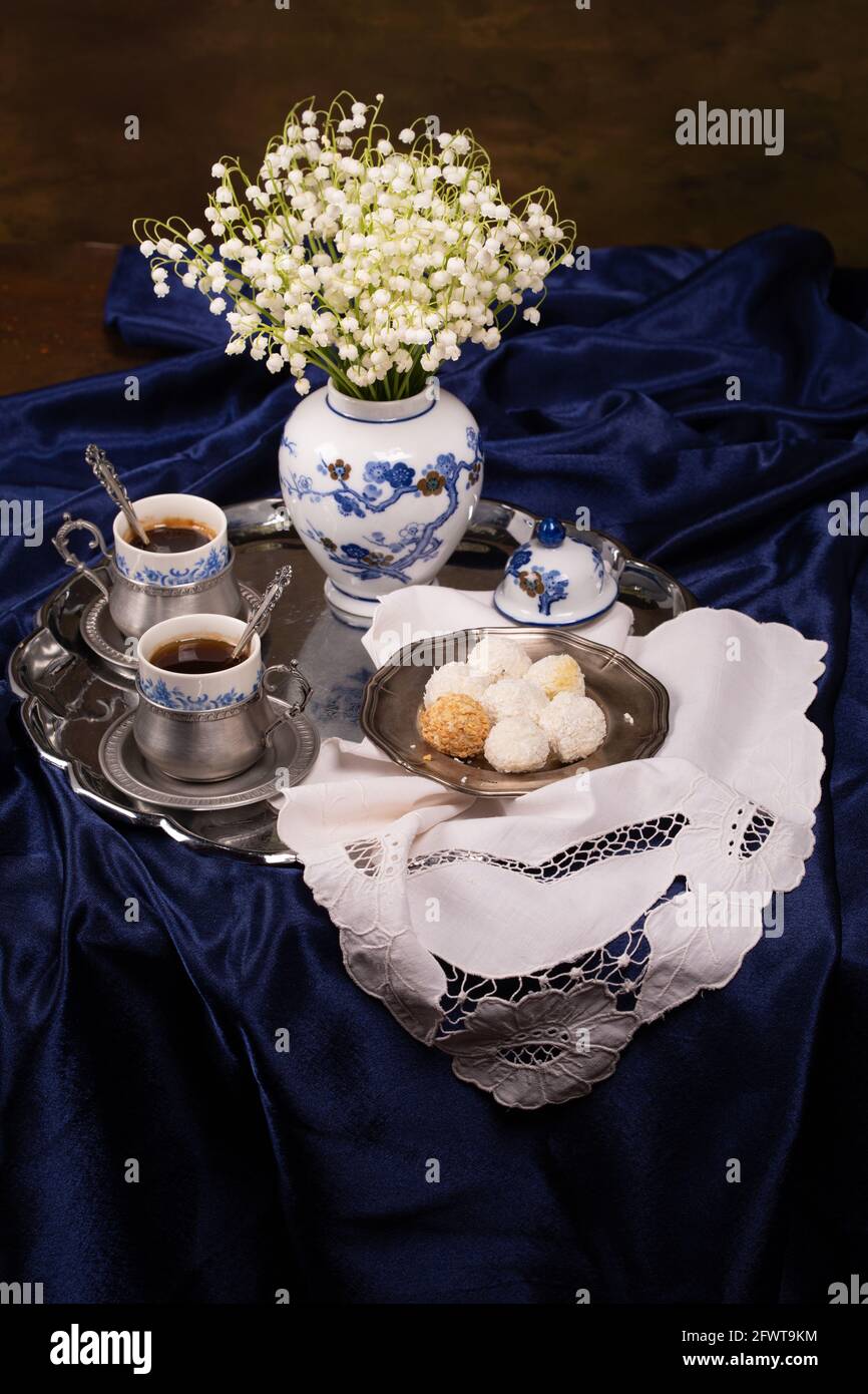 Still life with a bouquet of lilies of the valley and cups of coffee on ...