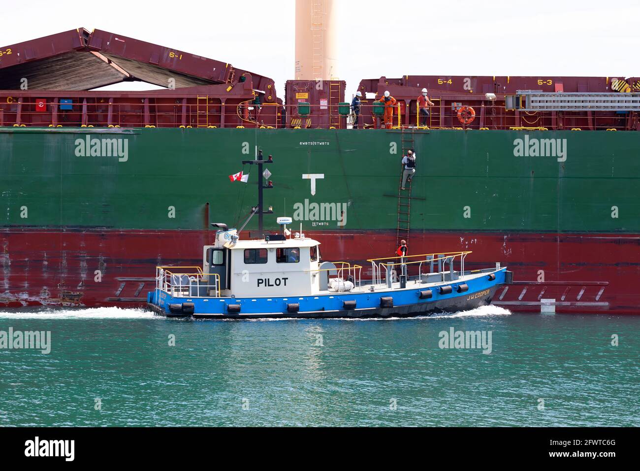A pilot boarding a ship from a pilot boat while underway Welland canal