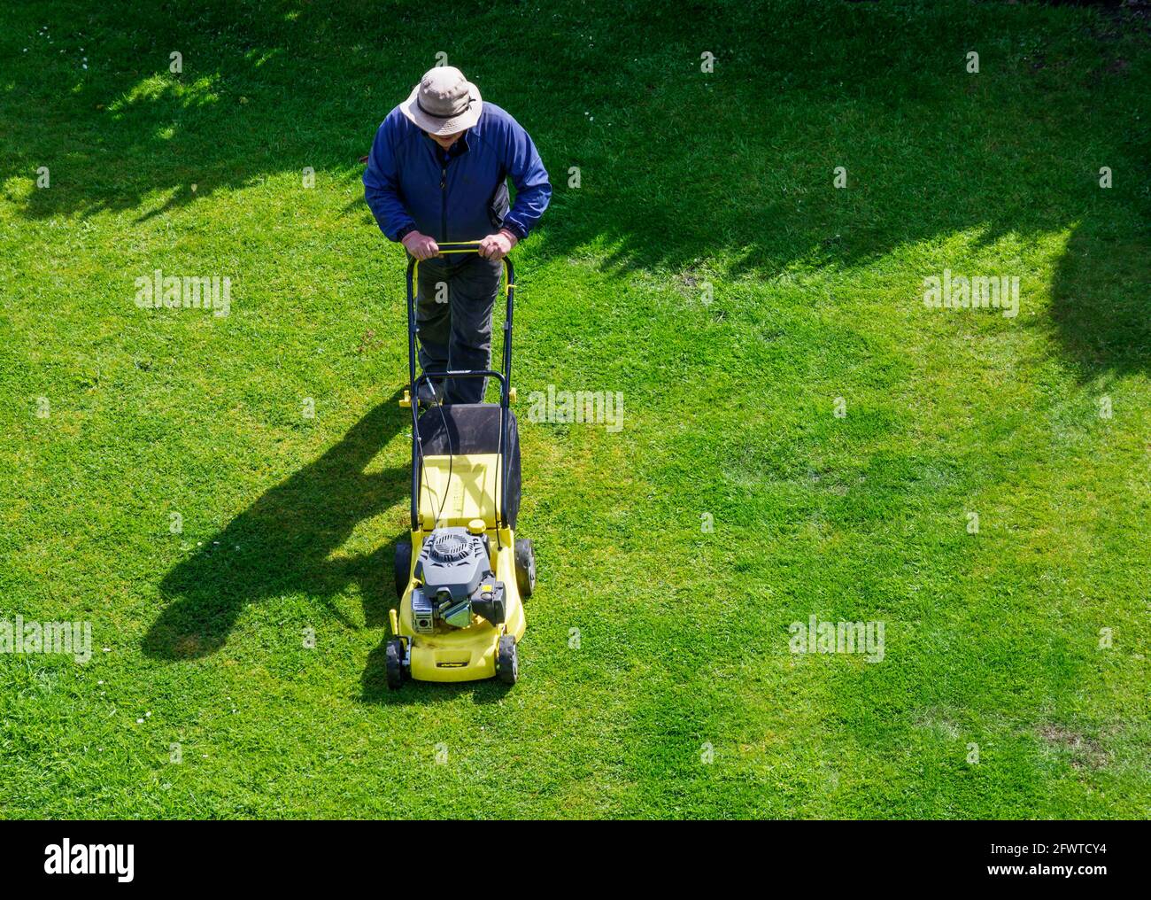 man tending his garden cutting the lawn with his mower Stock Photo