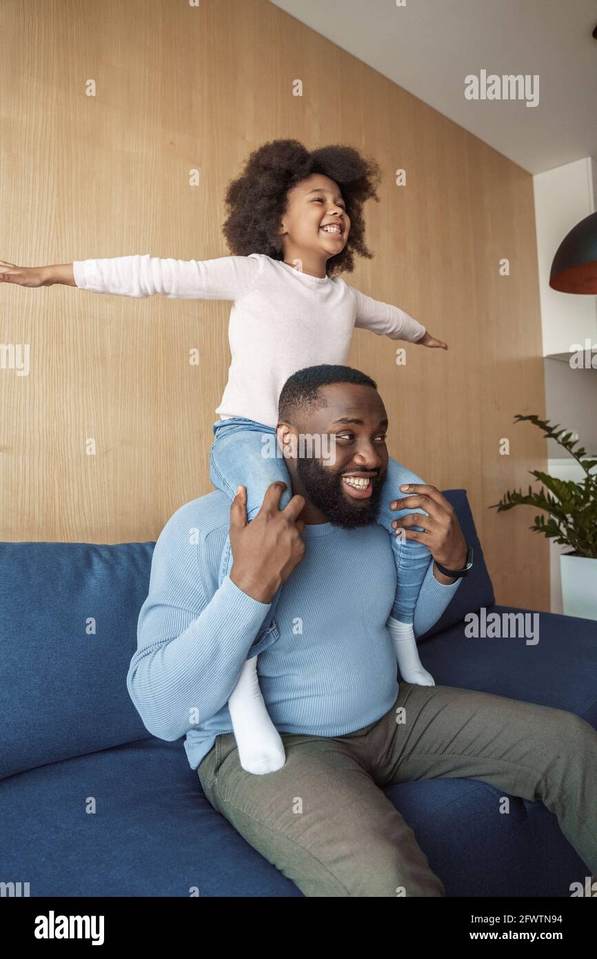 daugther sit and riding Black young father giving daughter piggyback ride when sitting on couch at  home Stock Photo - Alamy