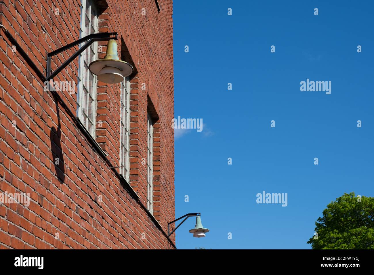 Helsinki / Finland - MAY 22, 2021: A vintage gas powered lamppost hanging on a red brick wall. Stock Photo