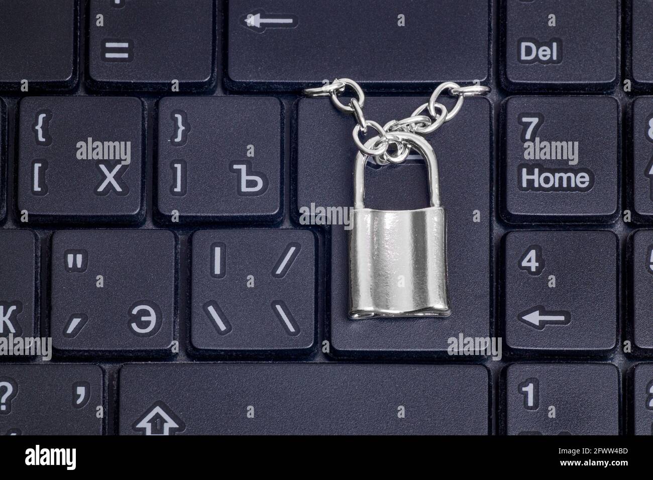 Closeup of a small locked padlock with a chain on a black laptop
