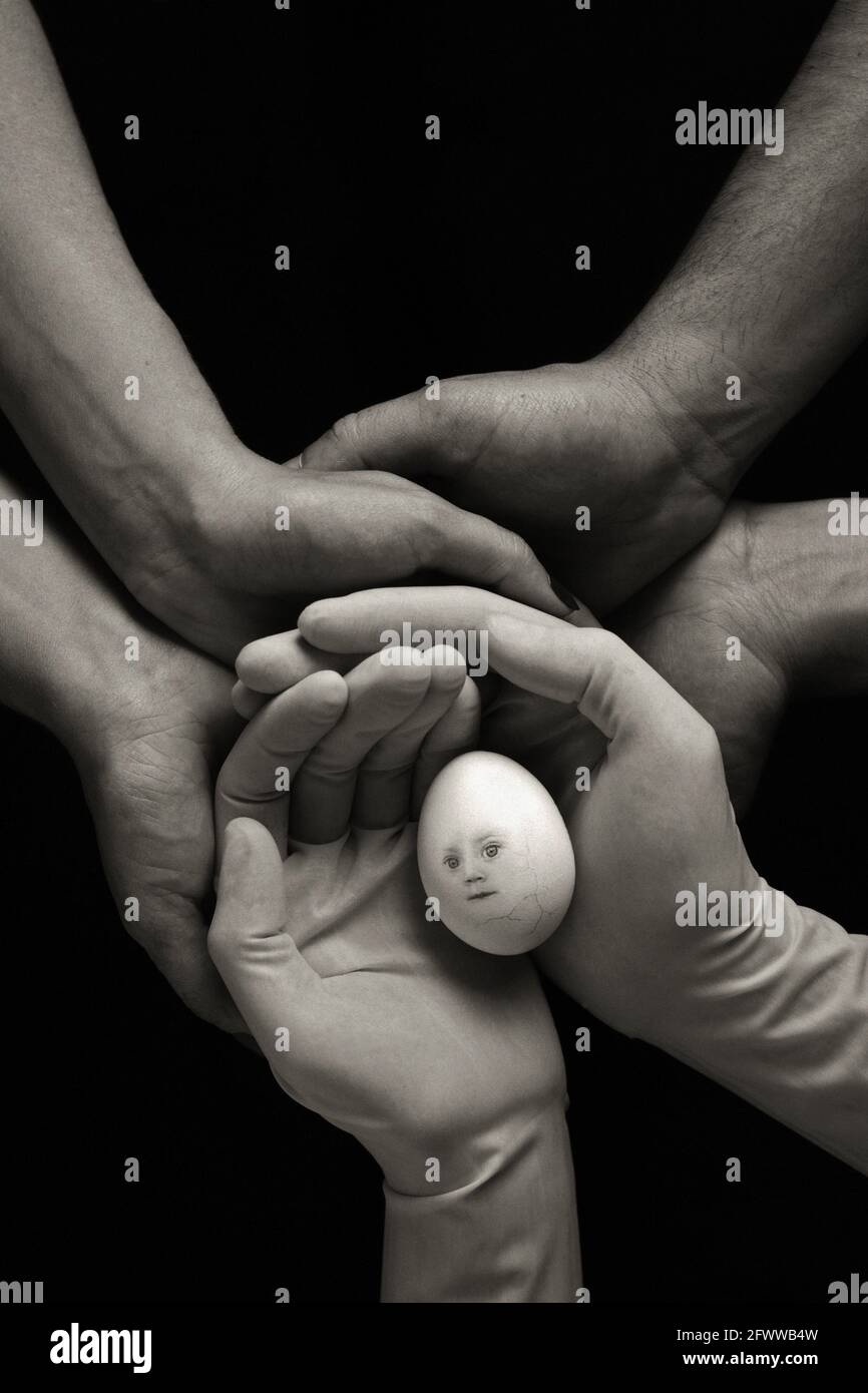 Surgical gloves and the hands of three care-givers form a nest for a cracked egg with a child's face; symbolizing teamwork; multi-discipline cooperation; and holistic care. Stock Photo