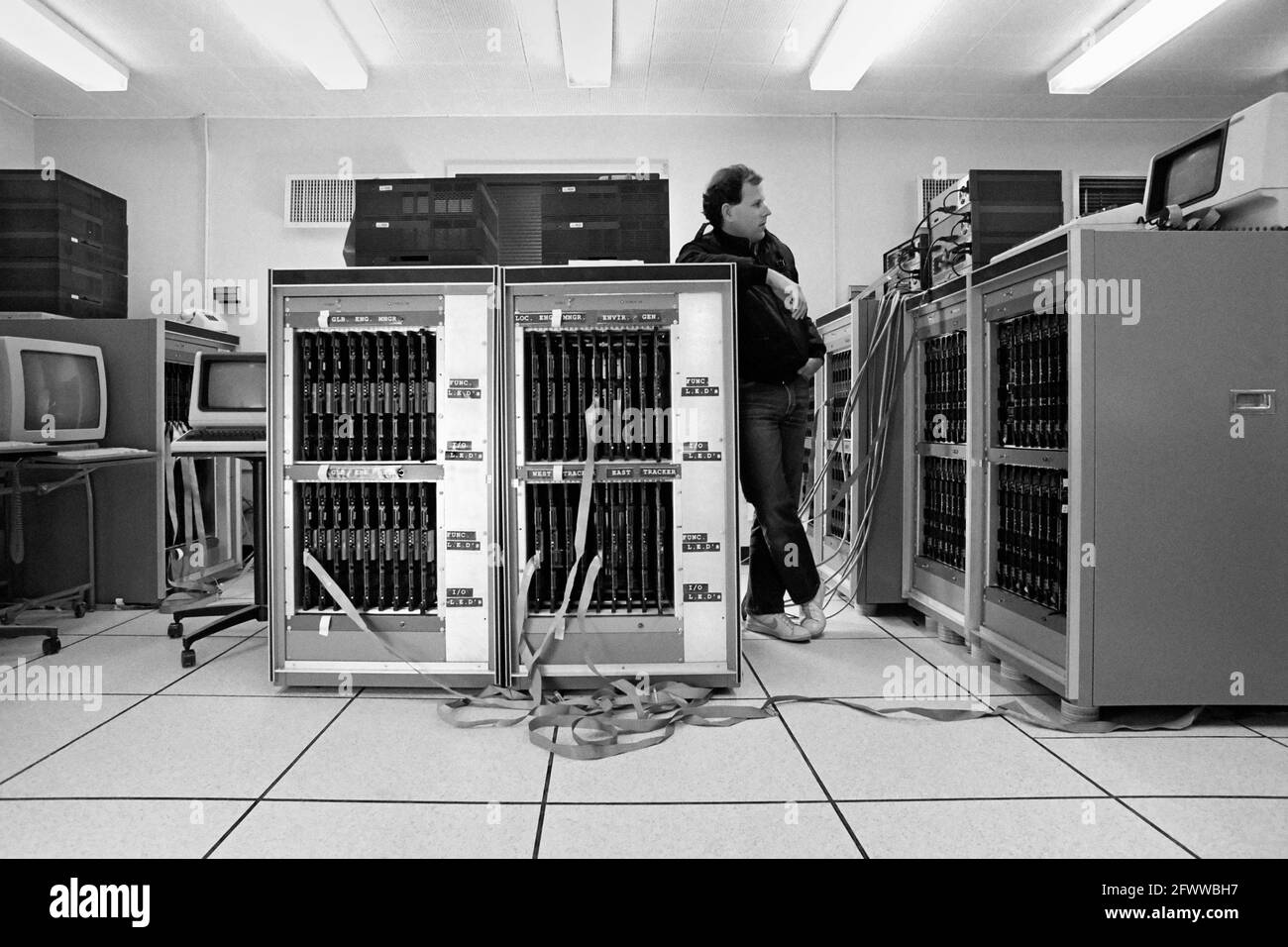 A JPL/Caltech project team leader conducts a 'Smoke Test'; monitoring the Mark III Hypercube supercomputer's functions as the size is ramped up. Each board comprises a node in the parallel-computing whole. The Mark III Hypercube integrated 128 nodes; each node having the power of 25 VAX minicomputers.? The peak speed was 2 billion floating point operations per second.? It was built with Motorola 68020 microprocessors and was a joint endeavor of Caltech and JPL.? Stock Photo