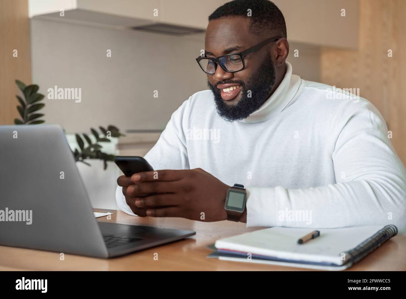 Young smiling african american man relaxing using laptop and mobile phone Stock Photo
