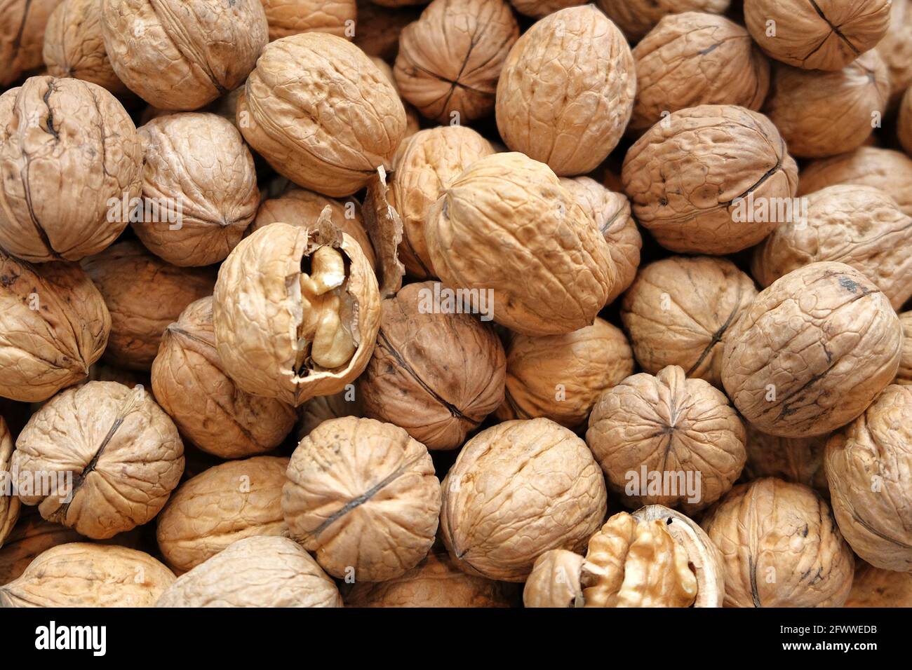 Walnut kernels and whole walnuts on rustic old wooden table. Stock Photo