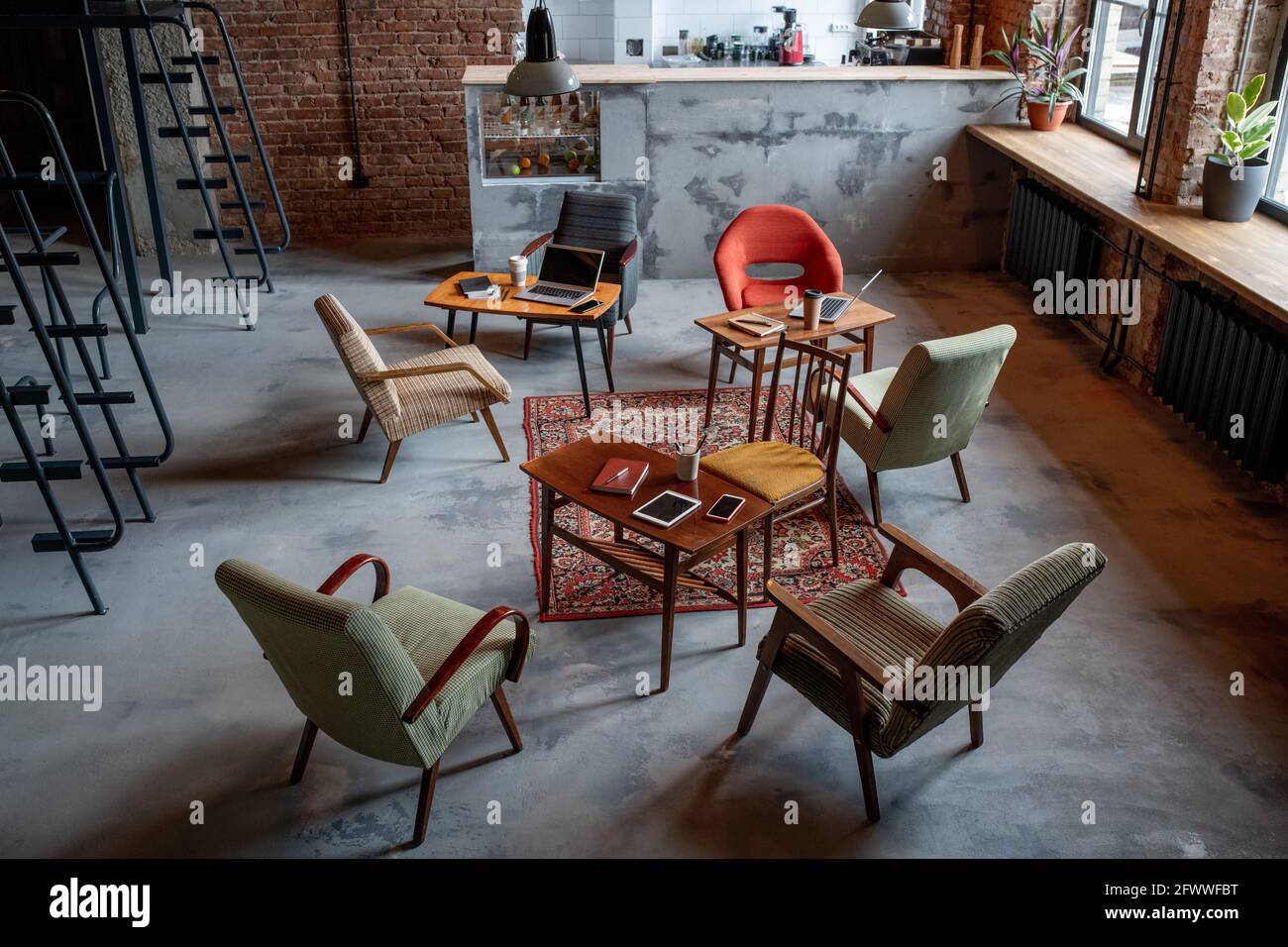 Several armchairs standing around tables with gadgets in office Stock Photo