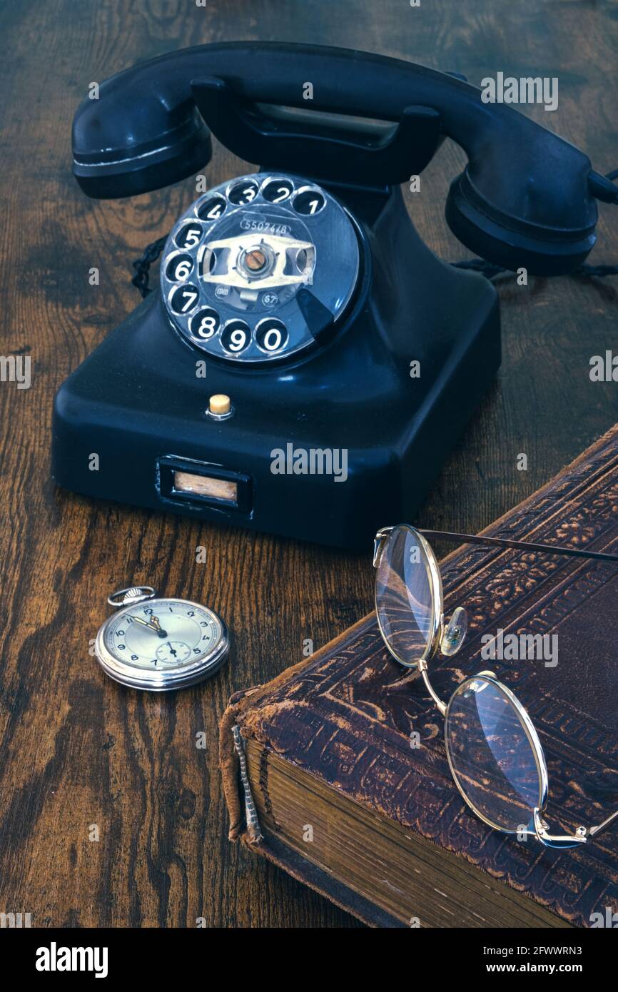 still life of old telephone, pocket watch, book andd glasses on wooden table Stock Photo