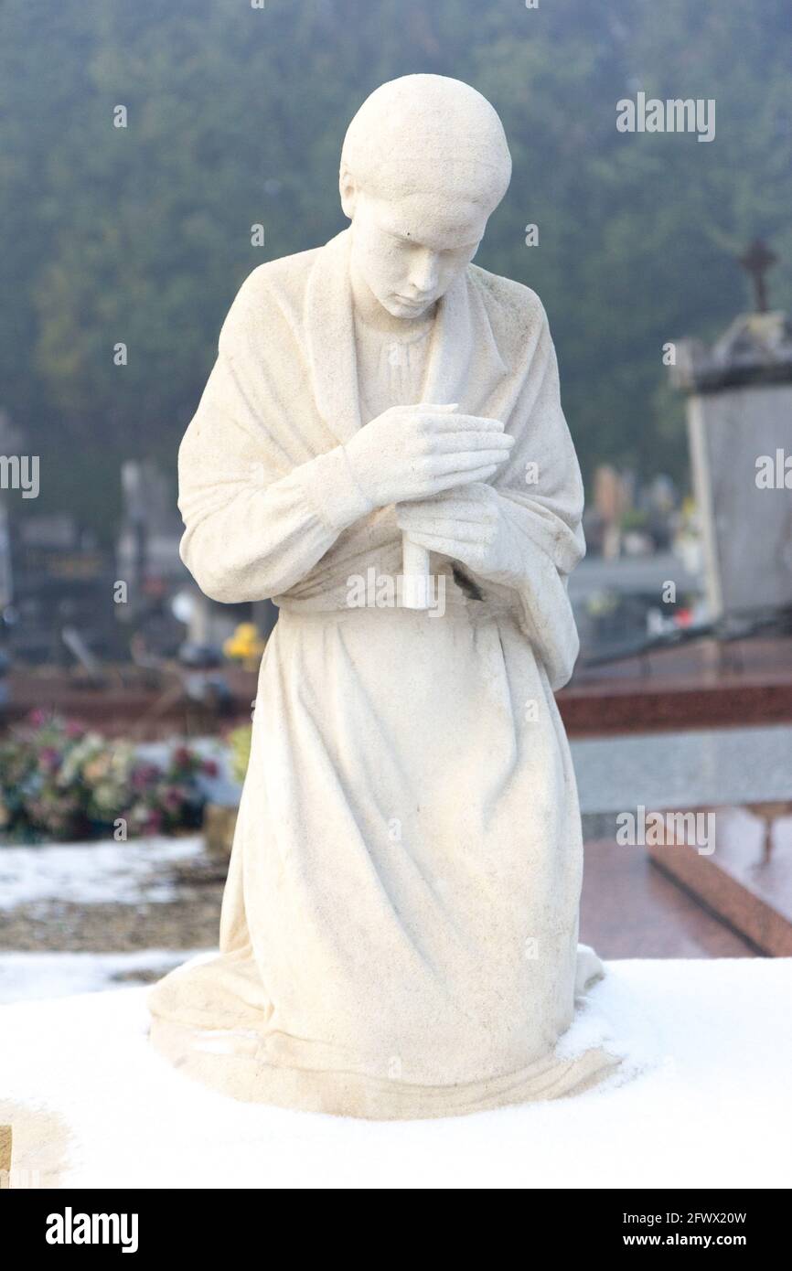 Valenciennes, France, 2017/01/02. Statue of a young girl with a candle on a tombstone at Saint Roch cemetery. Stock Photo