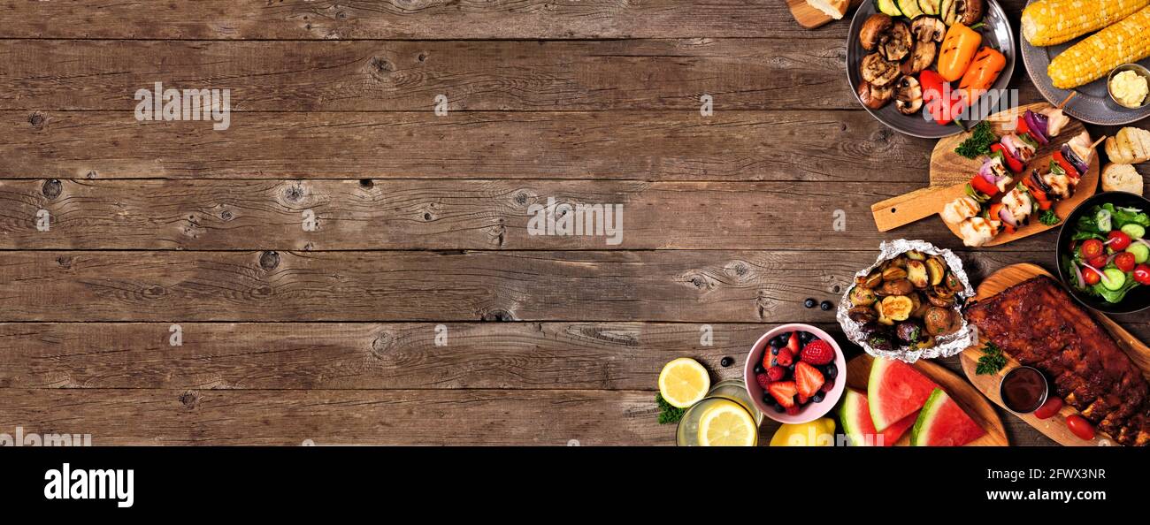 Summer BBQ or picnic food corner border over a rustic wood banner
