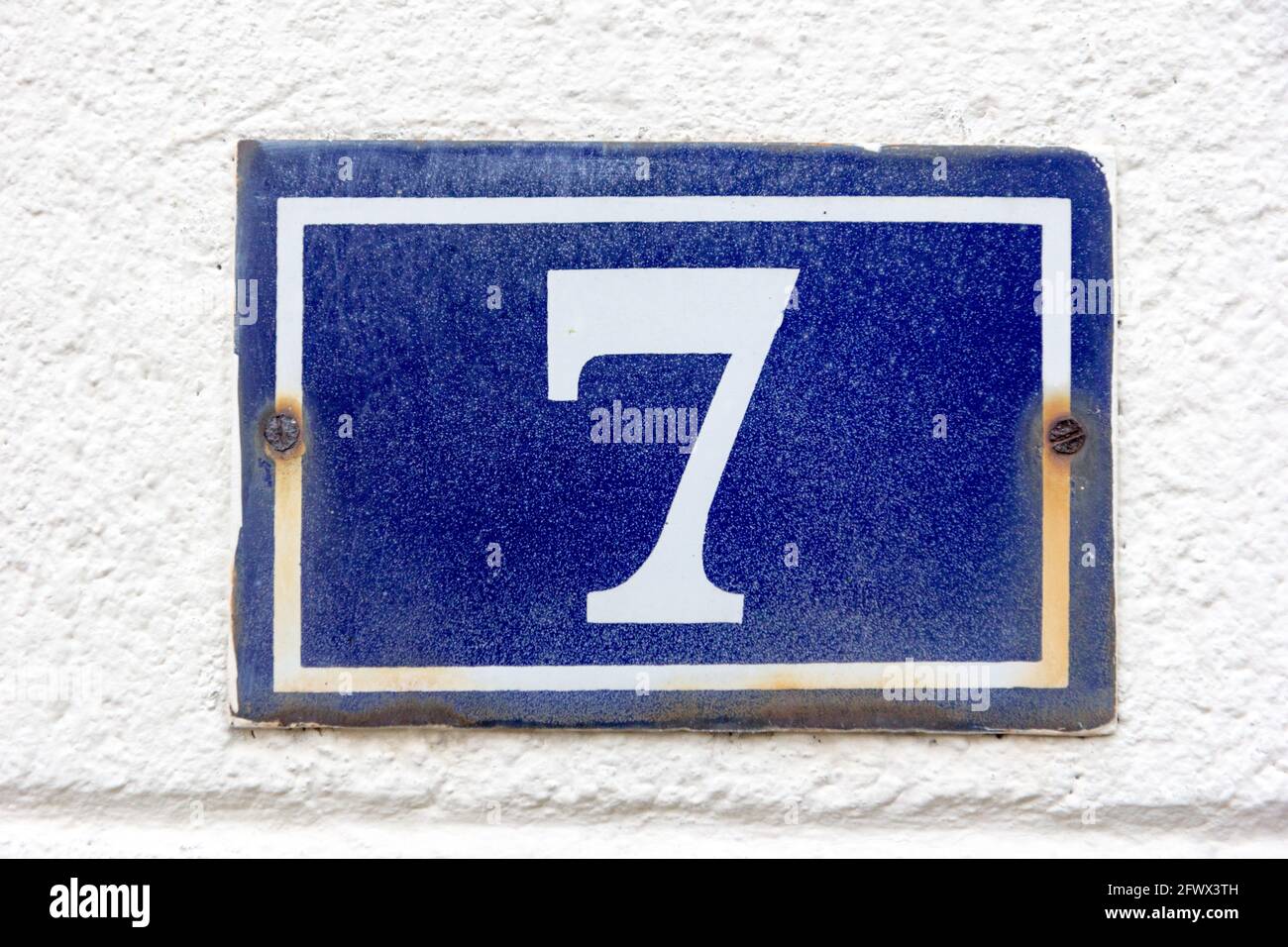 Number 7 (seven) in white on a blue metal plate Stock Photo