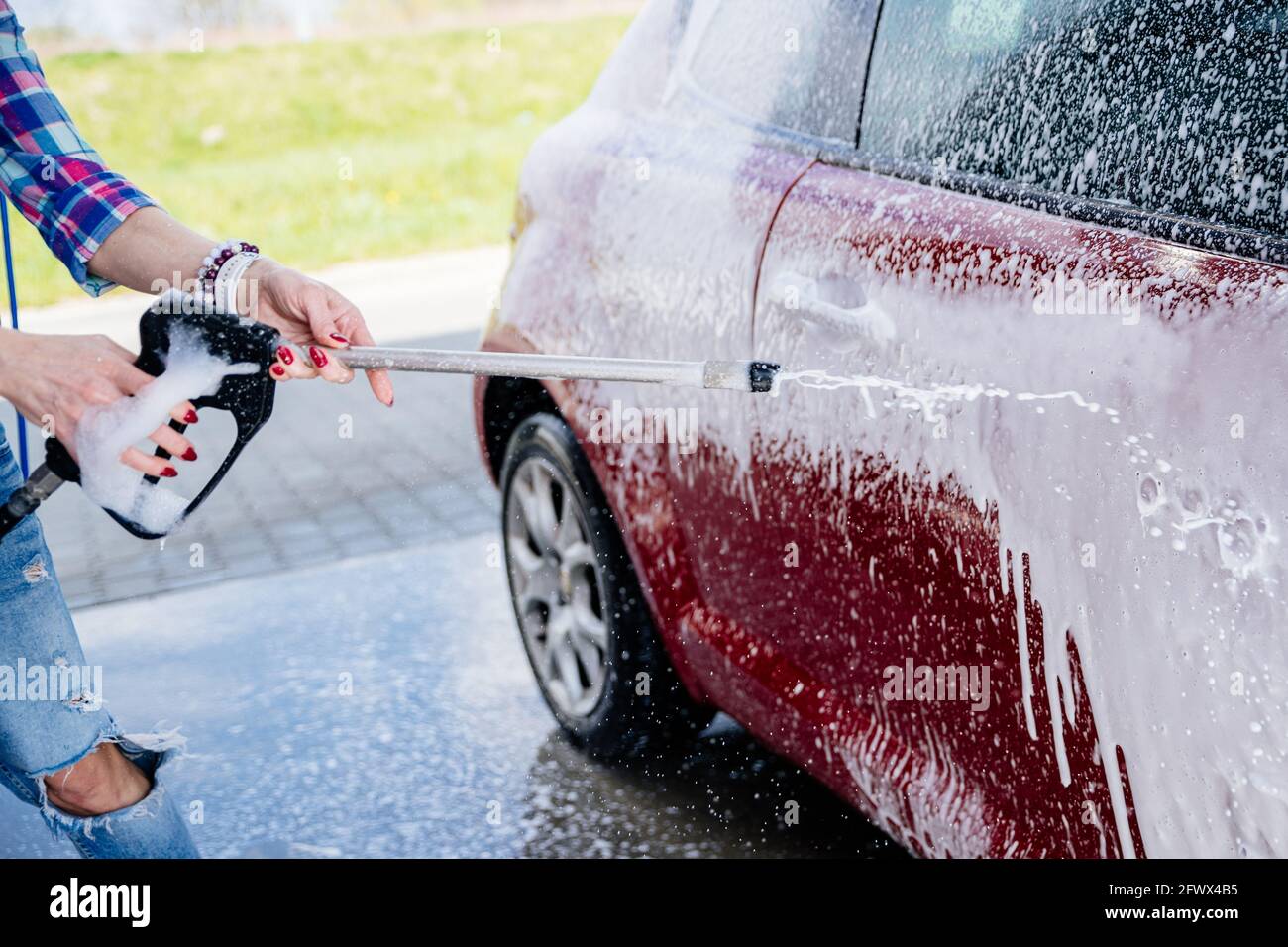 Modern car covered by foam. Manual car wash with pressurized water in car wash outside Stock