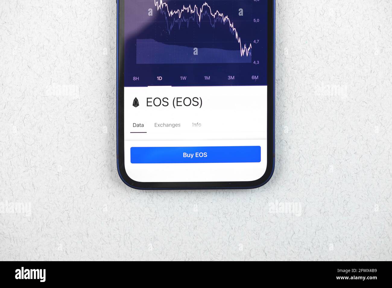 Buy EOS crypto currency, mobile phone app with button, concept of online trade, investment and coin exchange with smartphone, finance, office desk top Stock Photo