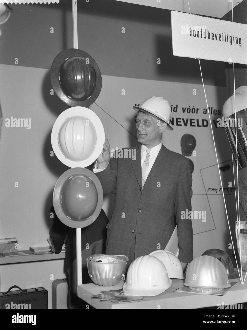 Opening Company Safety Exhibition at Amsterdam by State Secretary B. Roolvink . Roolvink, wearing safety helmet in helmet stand, April 17, 1961, HELMEN, Openings, STAND, The Netherlands, 20th century press agency photo, news to remember, documentary, historic photography 1945-1990, visual stories, human history of the Twentieth Century, capturing moments in time Stock Photo