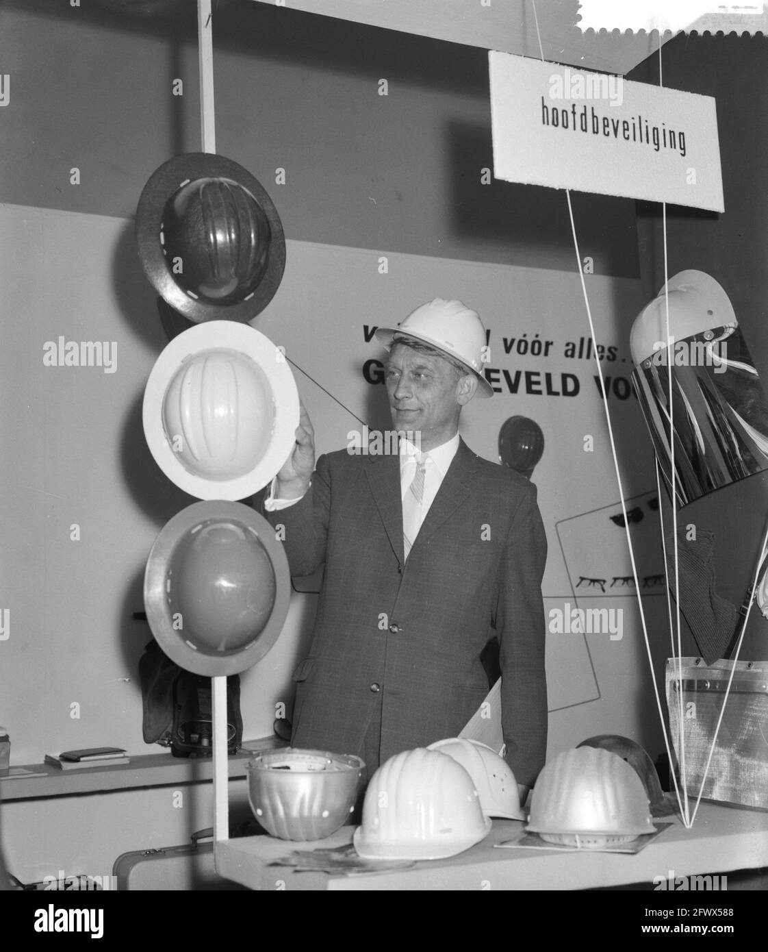 Opening of Business Safety Fair in Amsterdam by State Secretary B. Roolvink . Roolvink, wearing safety helmet in booth of helmets, April 17, 1961, HELMEN, Openings, booths, The Netherlands, 20th century press agency photo, news to remember, documentary, historic photography 1945-1990, visual stories, human history of the Twentieth Century, capturing moments in time Stock Photo