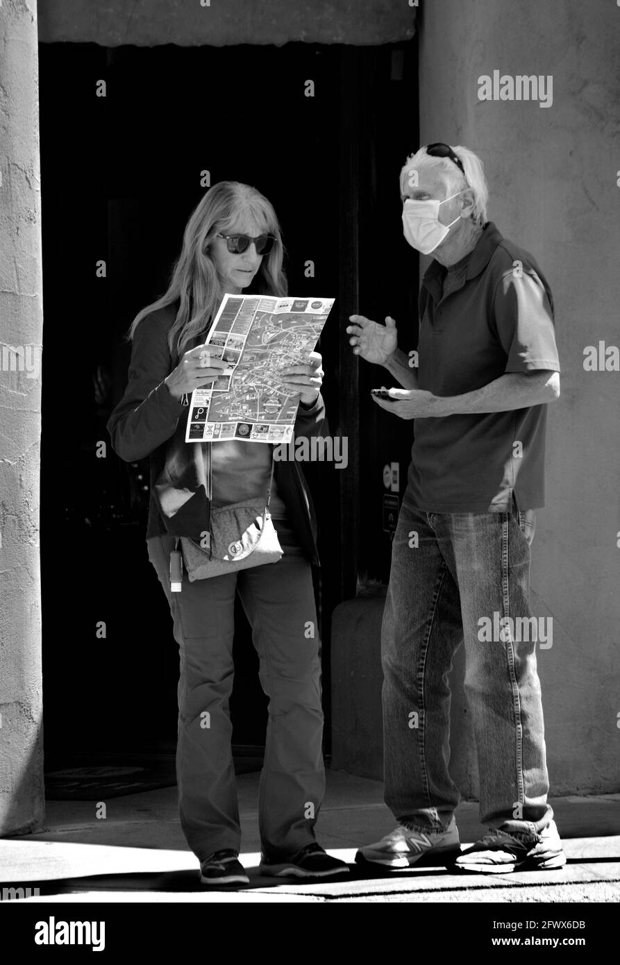 A couple visiting Santa Fe, New Mexico, consult an attractions map of the state capital city while standing outside a downtown art gallery. Stock Photo