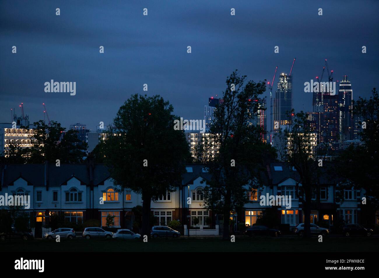 UK Weather, London, 24 May 2021: At dusk the stormy weather with heavy rain showers gives a dramatic skyline with central London's lights contrasting to the suburban houses that line Camberwell's Ruskin Park. AnnaWatson/Alamy Live News Stock Photo