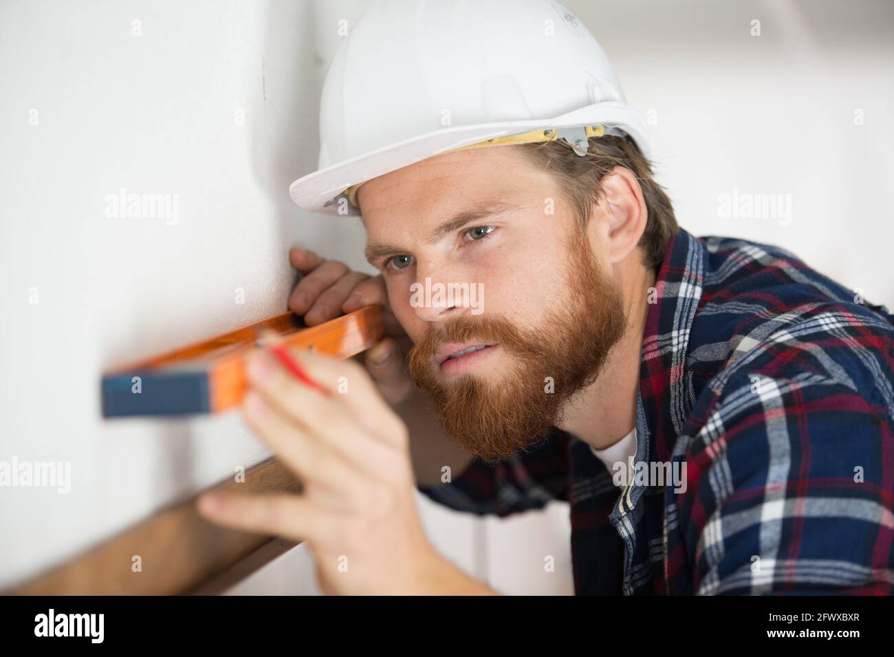 concentrated man using spirit level on wall Stock Photo