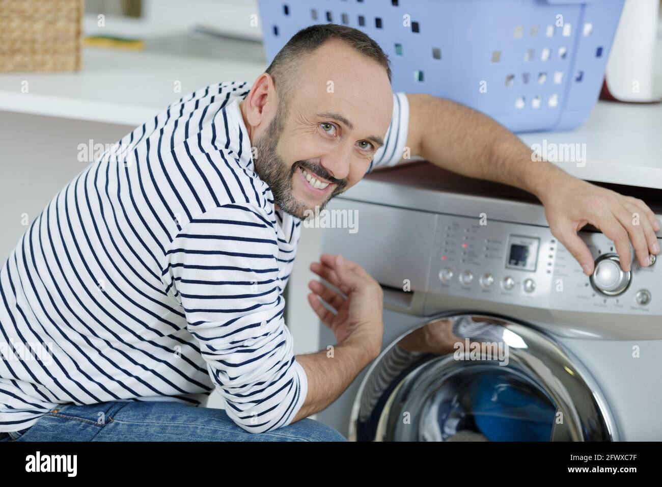 man using washing machine in kitchen Stock Photo