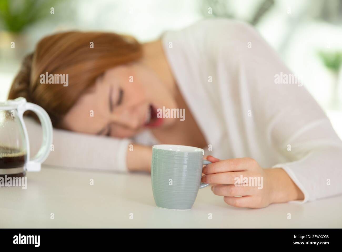 tired sleepy woman holds a cup of coffee Stock Photo