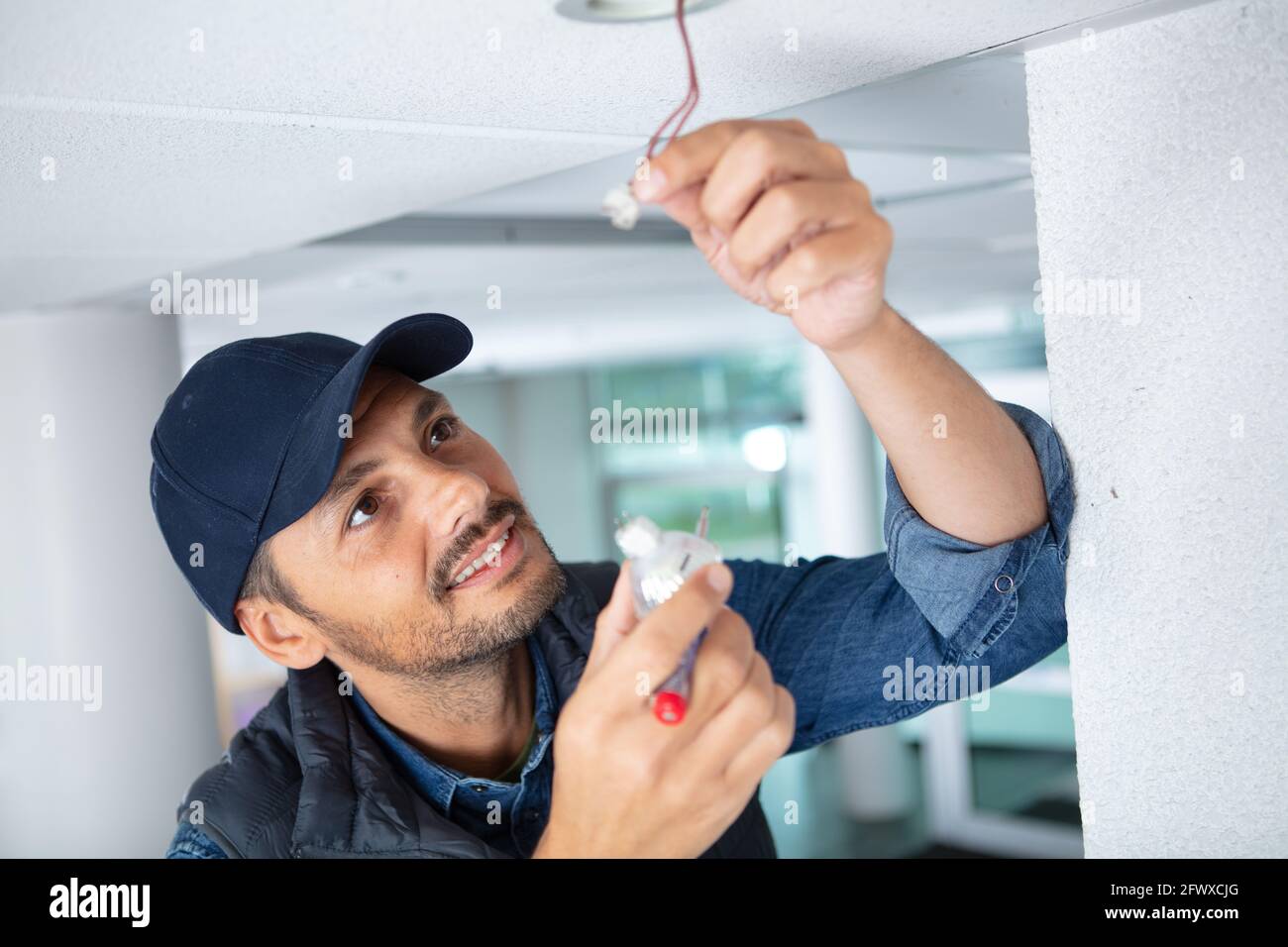 handsome young builderis twisting the light bulb in Stock Photo