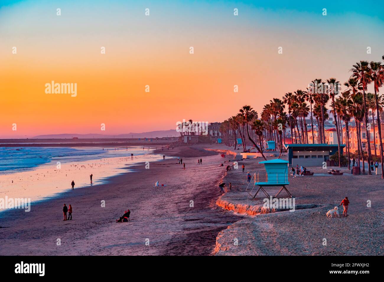 People sit and stroll at sunset on the beach in Oceanside, California. This is next to Carlsbad and San Diego. Stock Photo