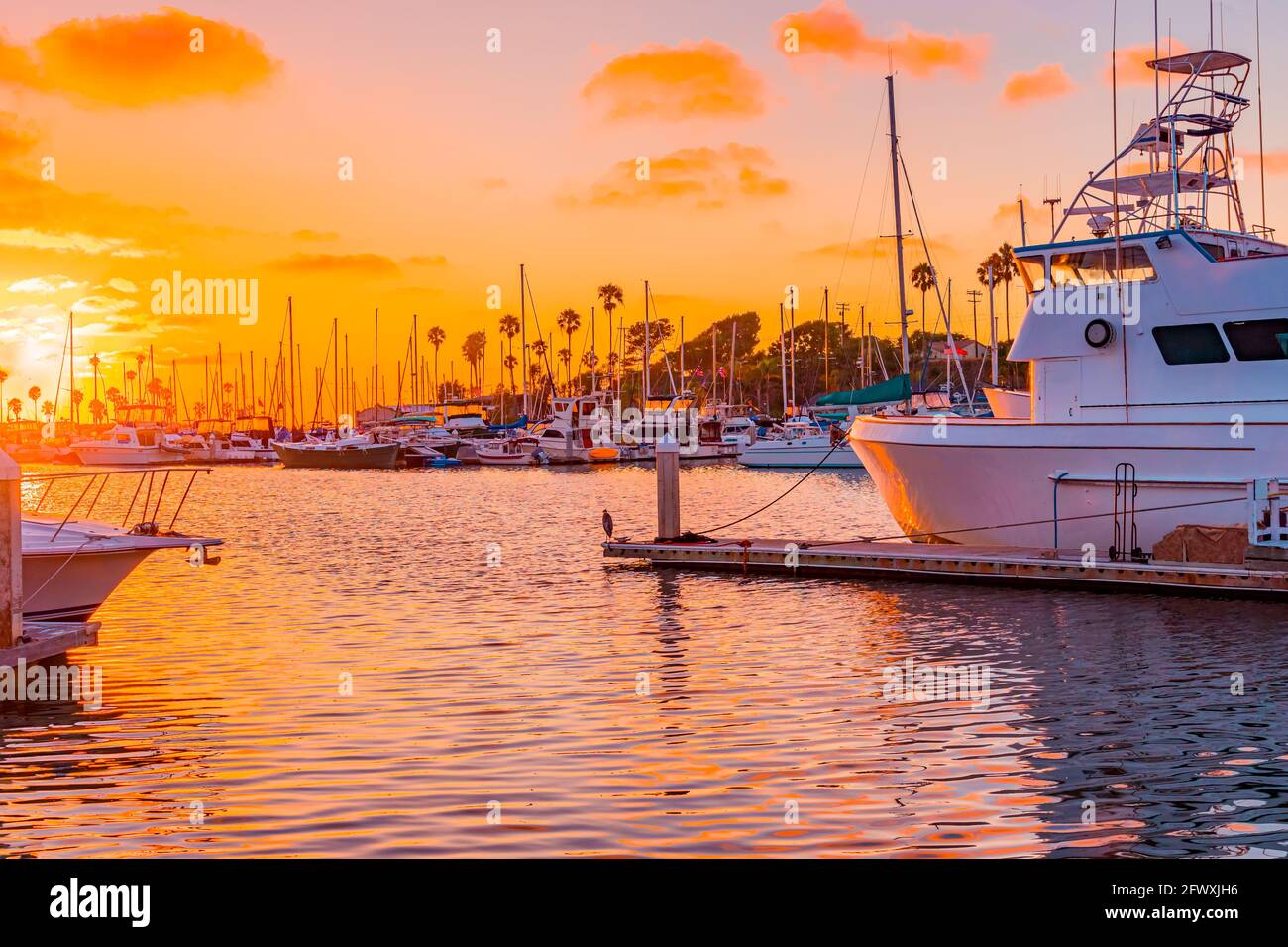 Oranges and pinks highlight all the boats, water and sky in Oceanside Harbor, near Carlsbad, California in Southern California. Stock Photo