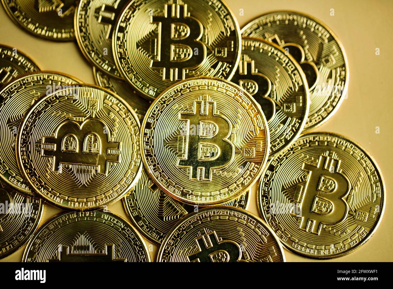 Image of stack of bitcoins against golden background. Cryptocurrency concept. Stock Photo