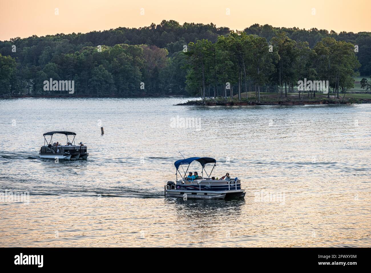 Families relaxing on pontoon boats at sunset on Lake Lanier along the shores of Lake Lanier Islands resort complex in North Georgia. (USA) Stock Photo