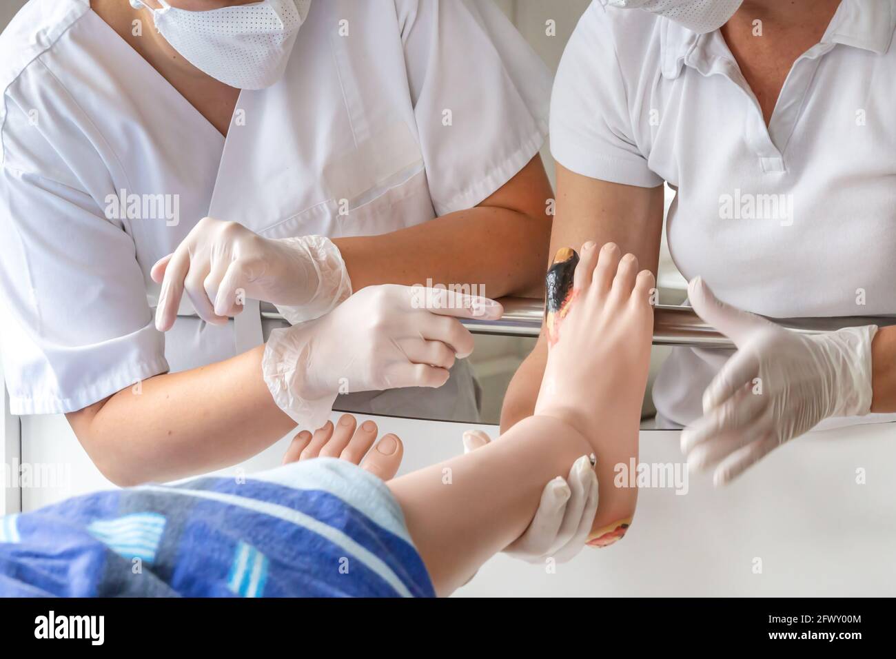 Two education nurses demonstrating screening and observation of wounds with help of a nursing puppet Stock Photo