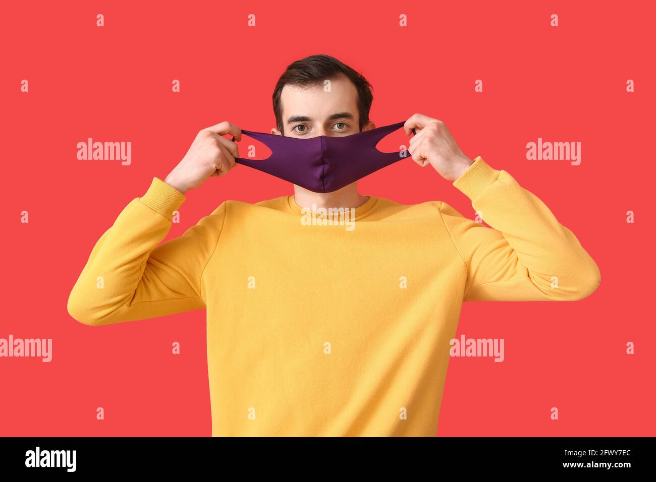 Young man wearing medical mask on color background Stock Photo - Alamy