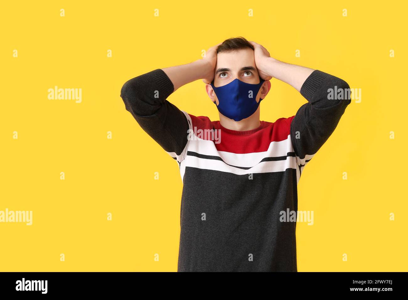 Stressed young man wearing medical mask on color background Stock Photo ...
