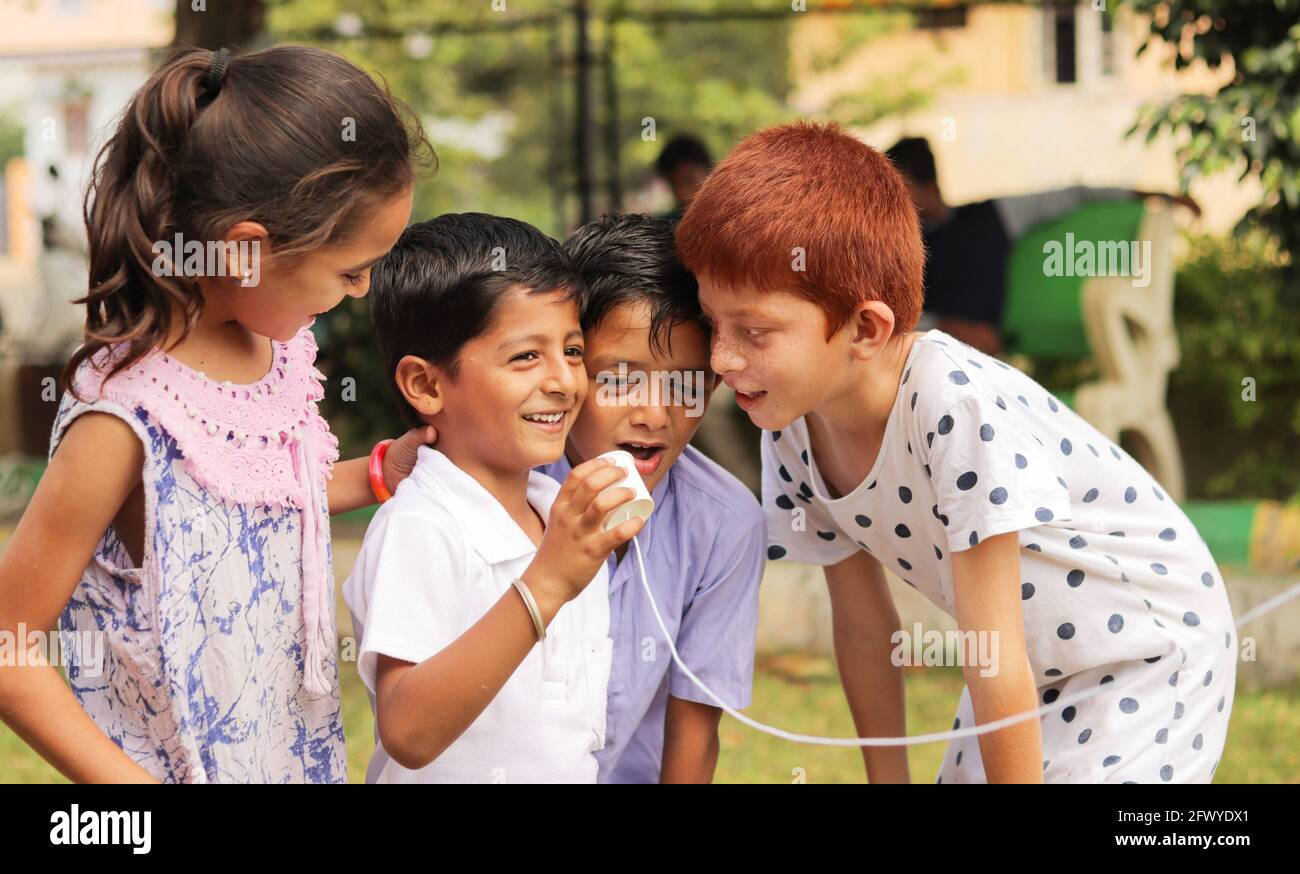 group of children having fun by playing with String Telephone during holiday summer camp - Concept of brain development and socializing by playing Stock Photo
