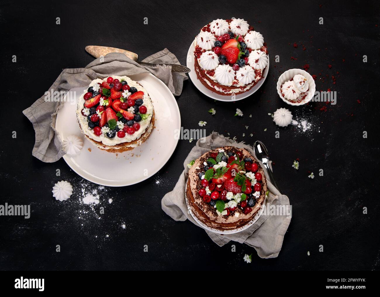 Assorted delicious and colorful homemade cakes with different type of filling on black background. Stock Photo