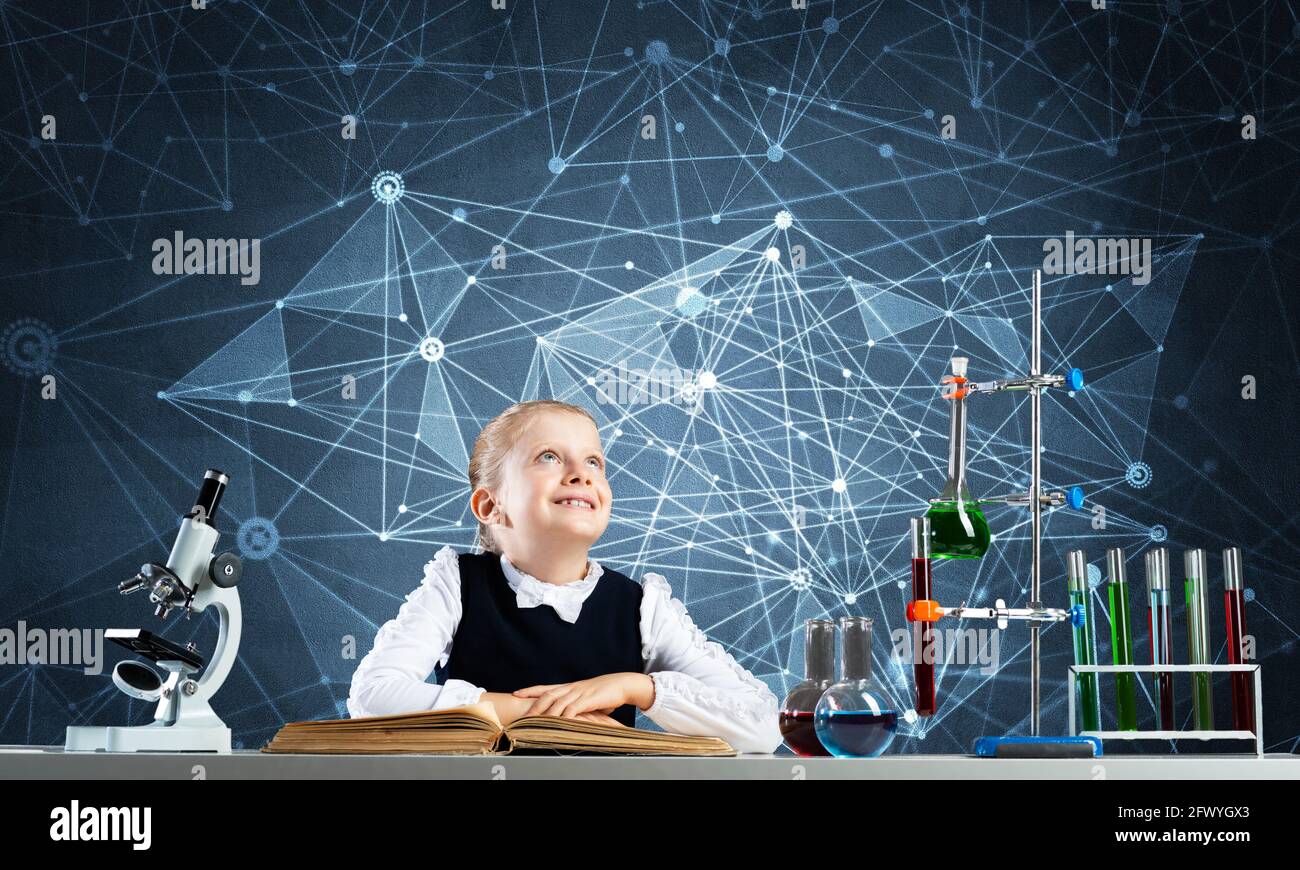 Smiling little girl sitting at desk with open book Stock Photo - Alamy