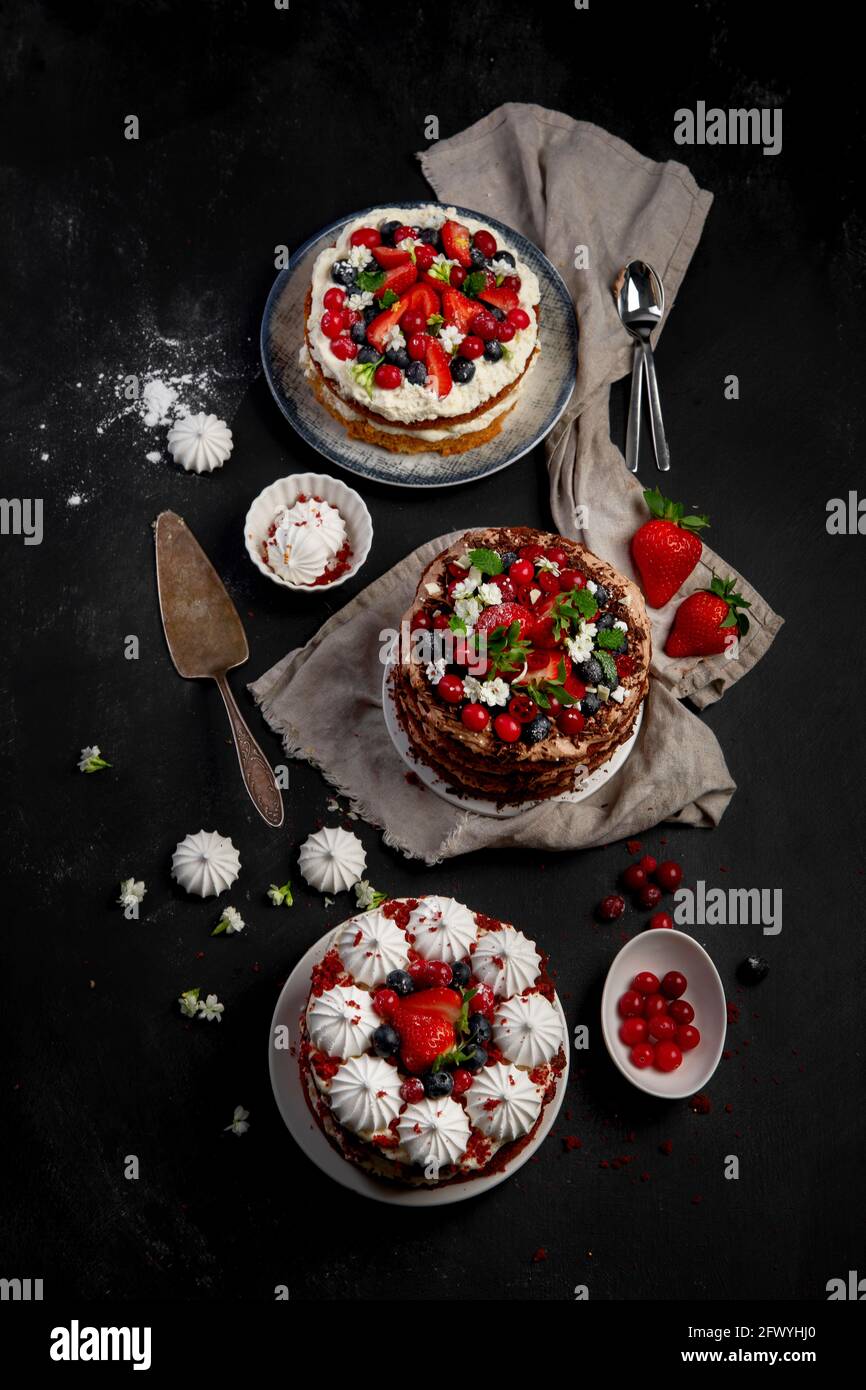 Assorted delicious and colorful homemade cakes with different type of filling on black background. Stock Photo