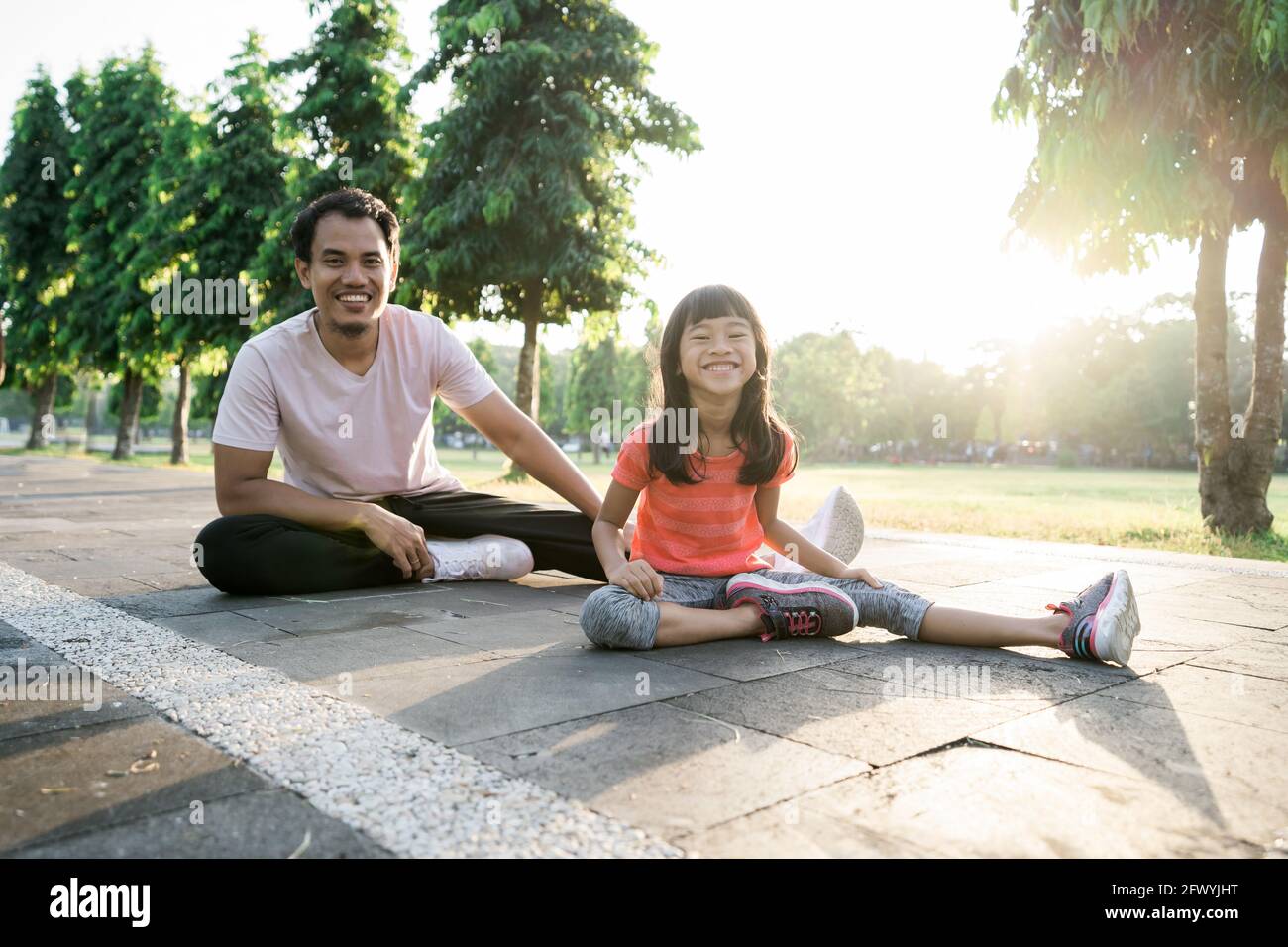 father and little daughter do exercises in outdoor. Healthy lifestyle of family with child Stock Photo