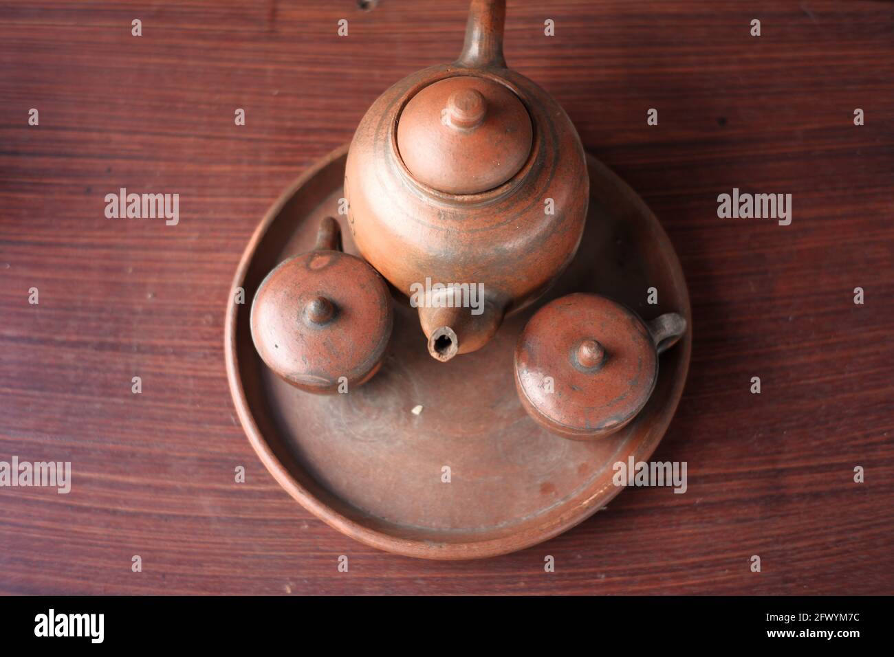 kettles and glasses handmade with clay materials. traditional Javanese kitchen tools used for warm drinks. Indonesian red kitchen utensil on a wooden Stock Photo