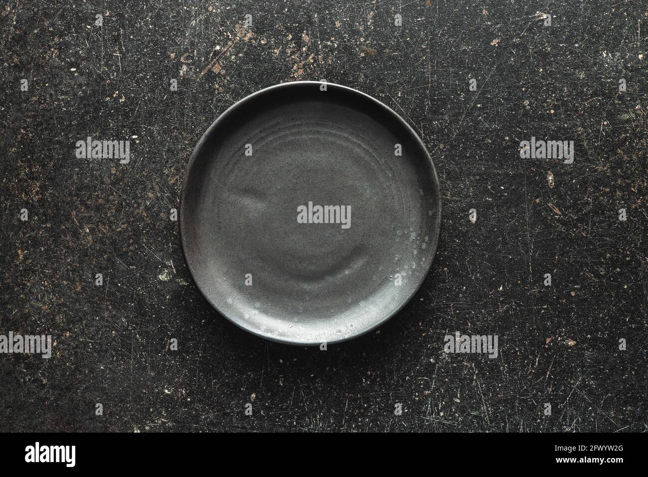 Empty vintage plate on black table. Top view. Stock Photo