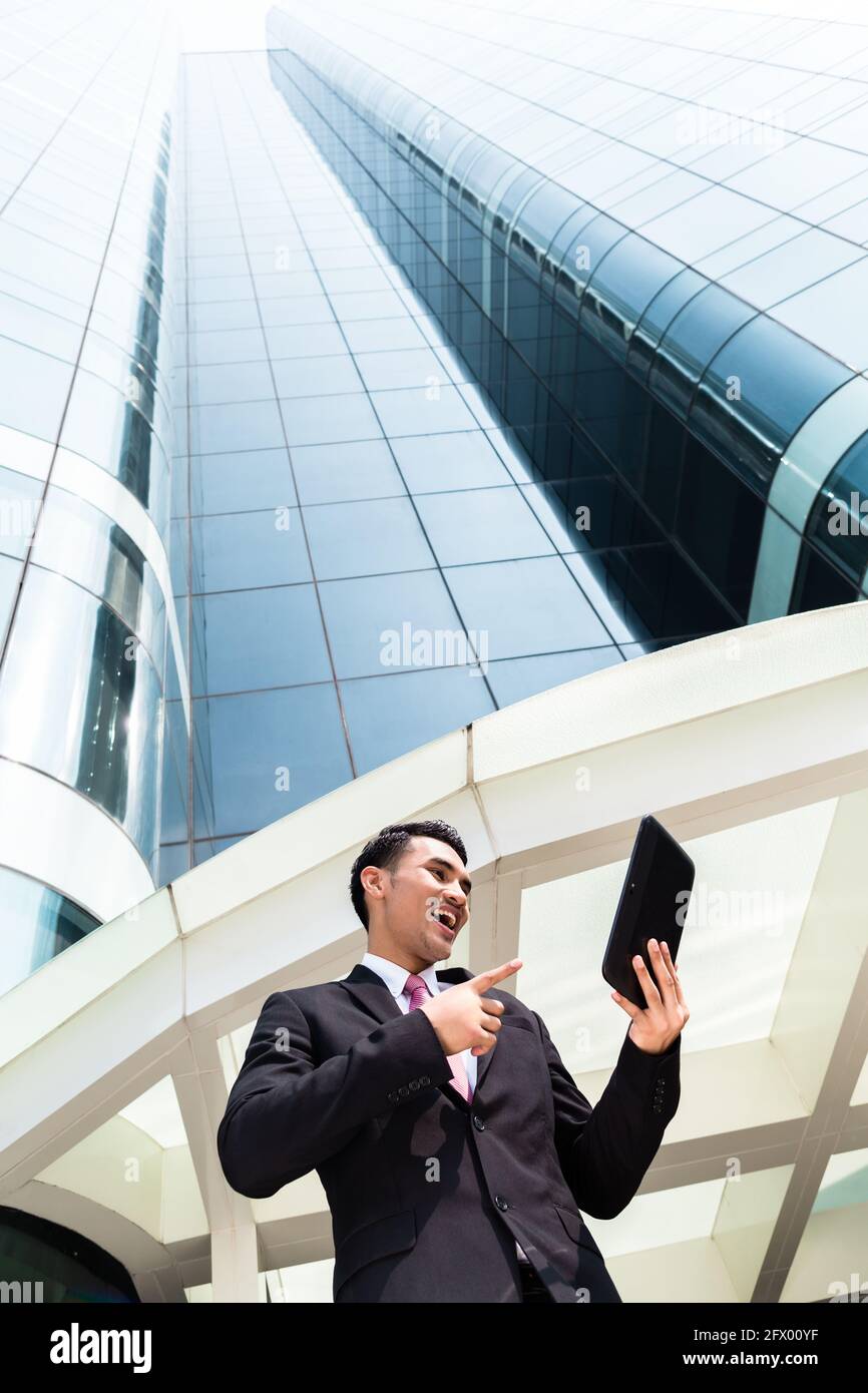 Asian businessman checking outside mails on tablet computer in front of ...