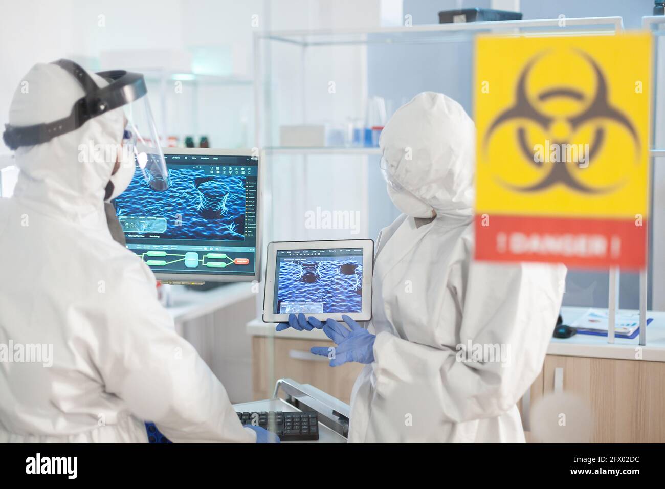 Healthcare doctors working in danger area of lab dressed in ppe suit during global pandemic. Group of doctors examining vaccine evolution using high tech for diagnosis against covid19. Stock Photo
