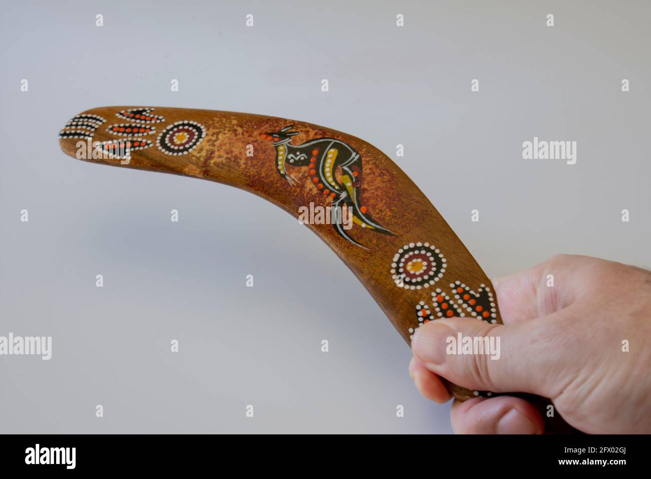 man holding colorful and ornate boomerang. australian souvenir, selective focus. isolated white Background. Stock Photo