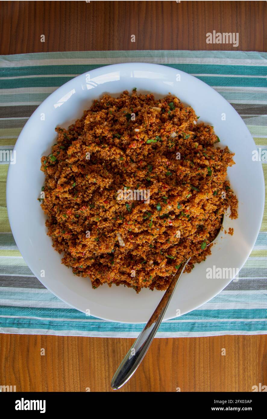 an aperitif from traditional Turkish cuisine; Kısır made with crushed wheat, tomato paste and finely chopped greens. Top view. Stock Photo
