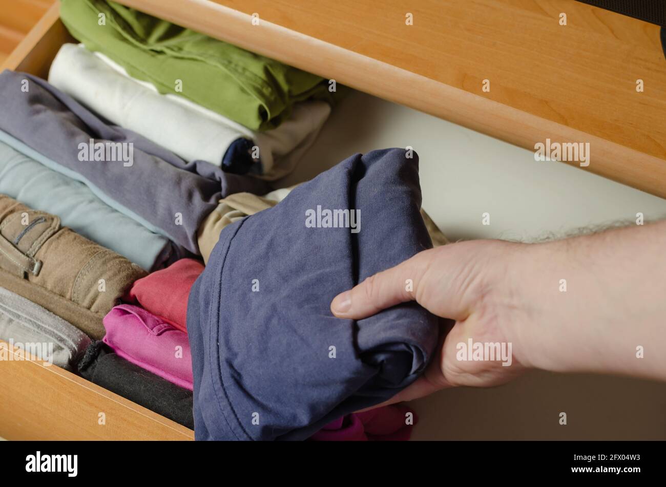 Concept Vertical Japanese clothes storage system. Multicolored shirts