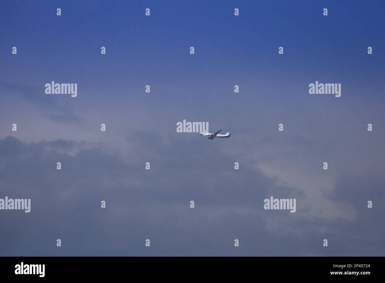 Propeller plane lit by the sun against a blue sky with white clouds and ...
