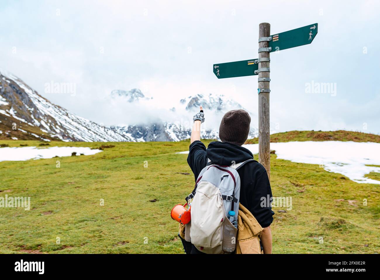 Back view of female backpacker pointing on arrow showing footpath ...
