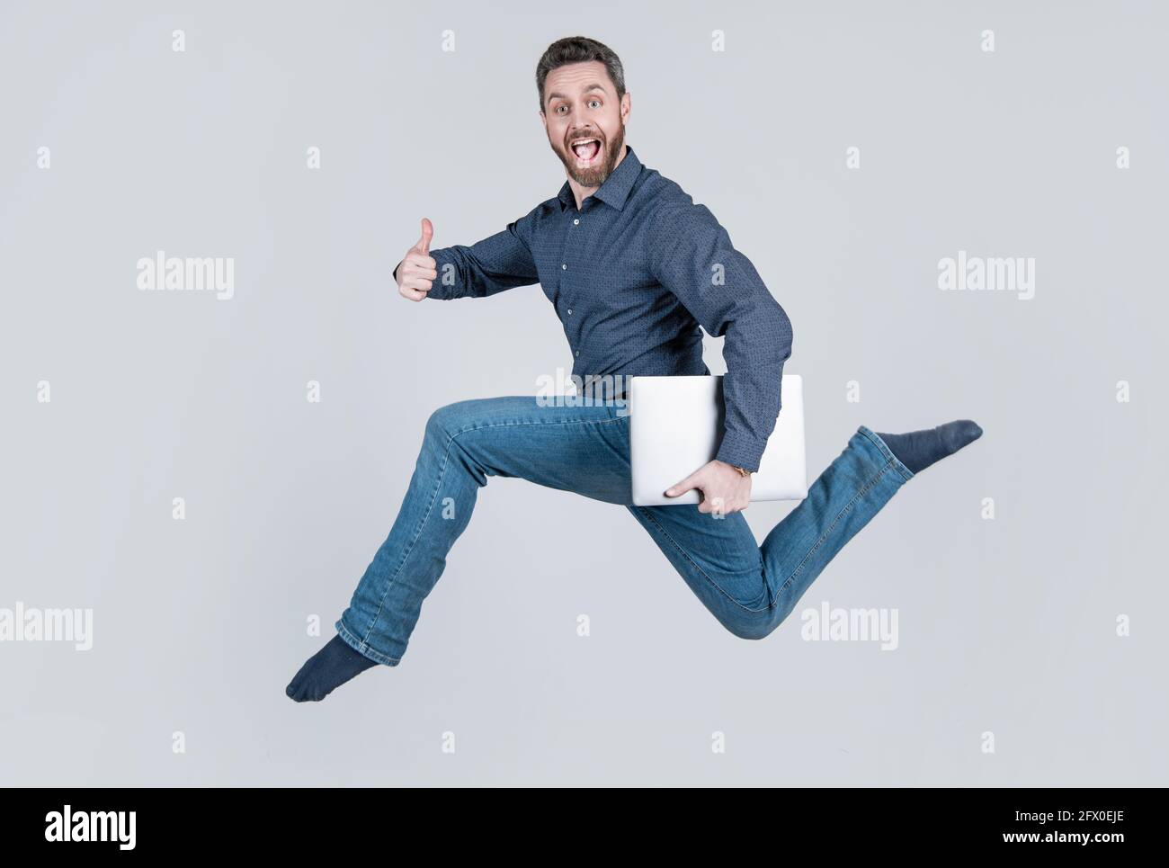 jumping man running while working online on laptop hurry up for shopping show thumb up, success. Stock Photo