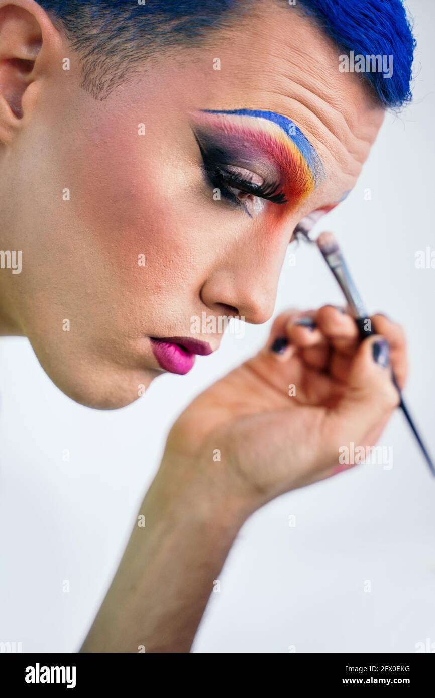 Side view calm male with blue hair applying drag makeup and reflecting in  round mirror in dressing room Stock Photo - Alamy
