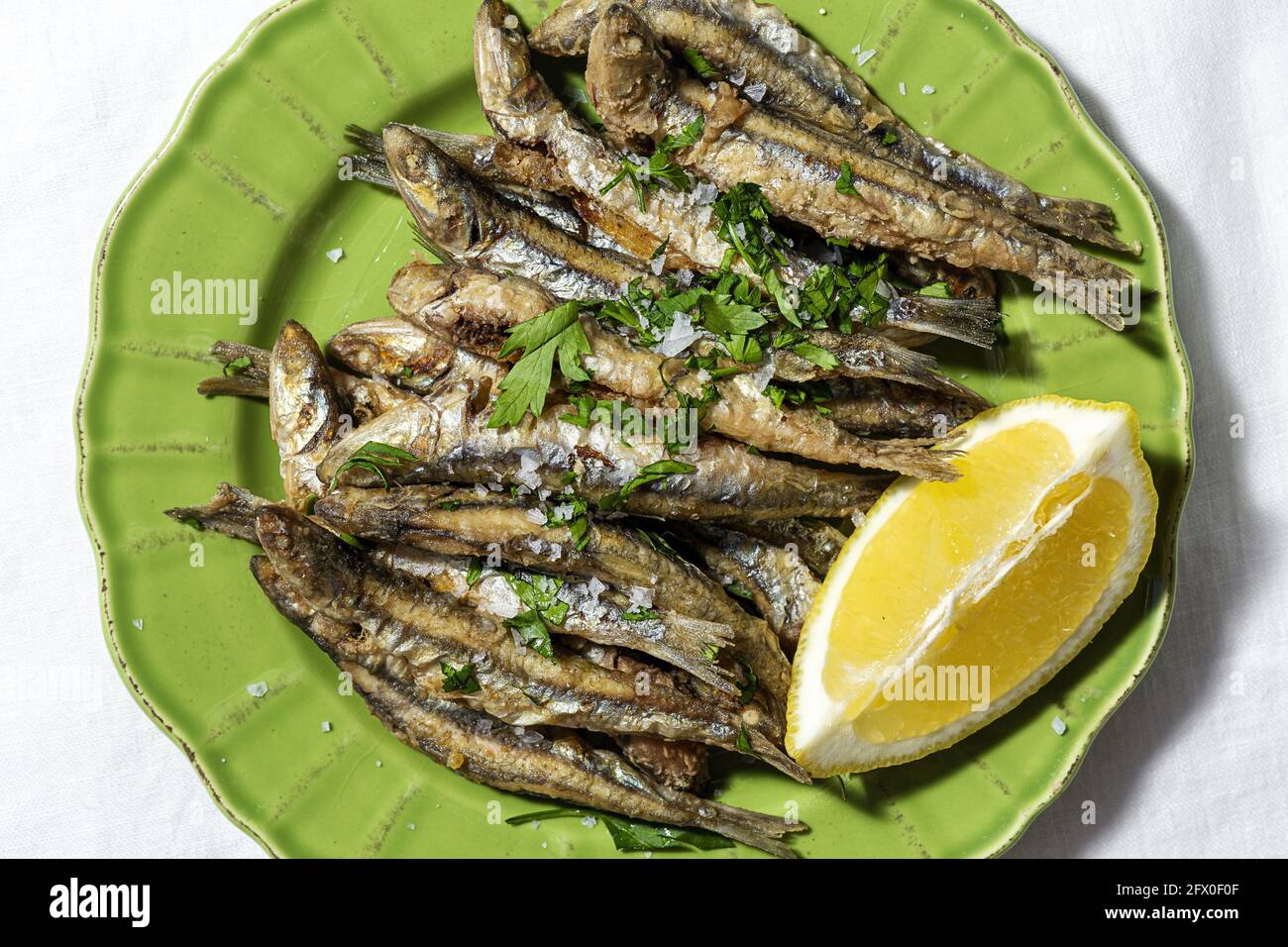 Top view plate of appetizing grilled anchovies served on table with piece  of lemon and fresh herbs in restaurant Stock Photo - Alamy