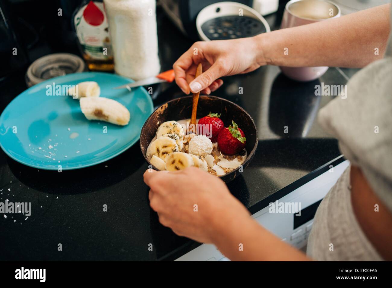 From above crop unrecognizable person topping tasty healthy porridge with banana and strawberries in kitchen Stock Photo